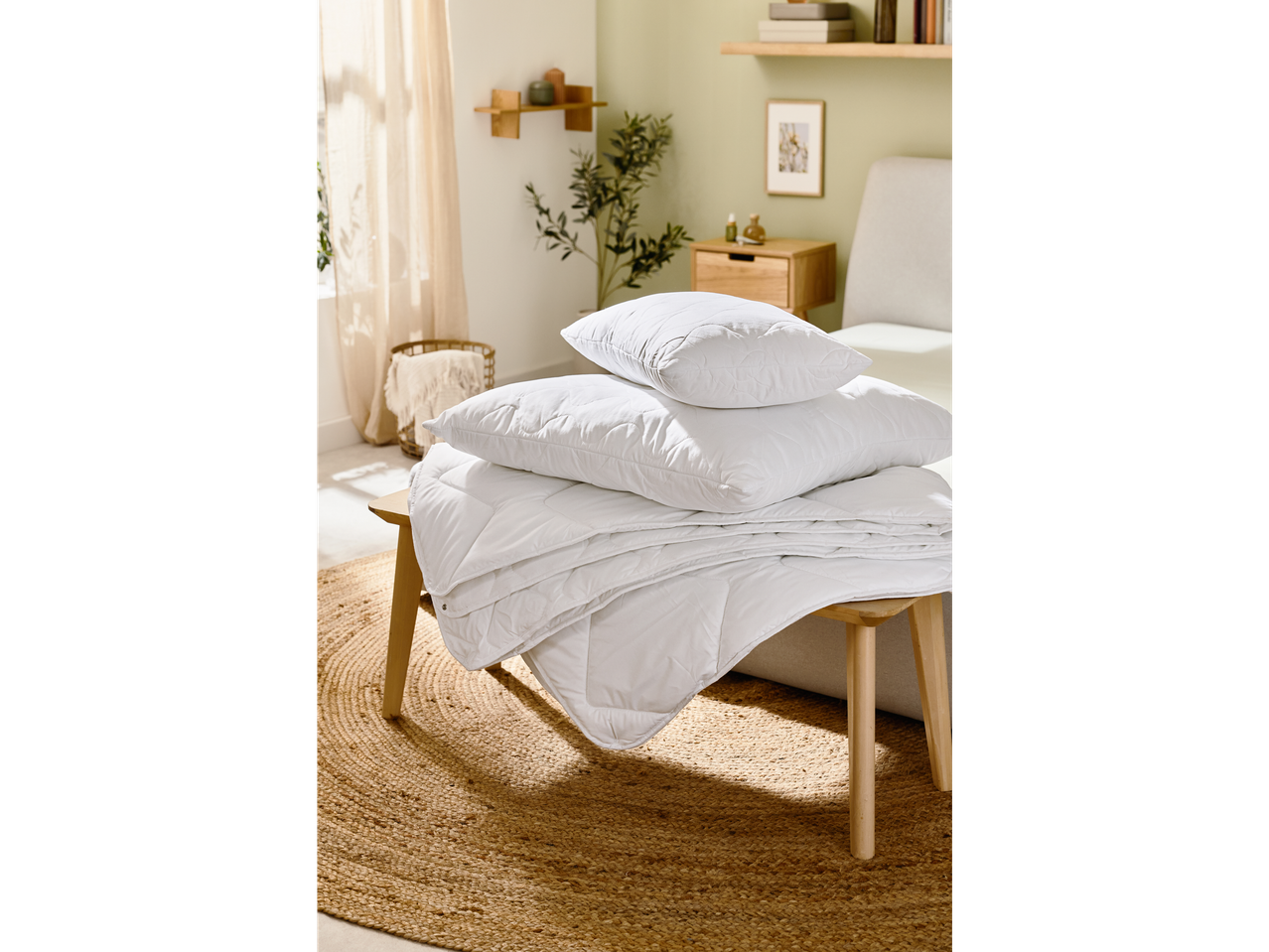 Folded duvet and pillows on a wooden side table.