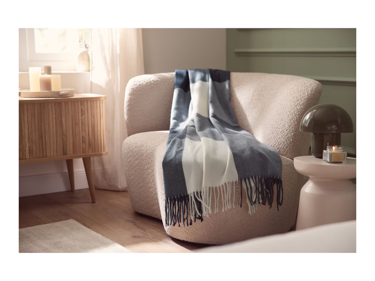 Cozy living room with a beige armchair, a blue and white striped throw, and a wooden side table.