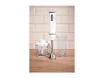 Hand blender set with chopper and measuring beaker on a wooden countertop.
