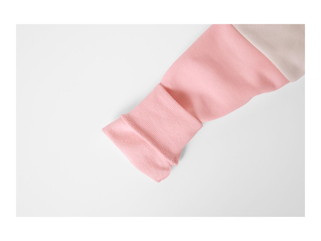 Close-up of a pink and beige color block sweatshirt sleeve.