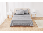Bedroom with light wood flooring, white nightstands, and gray patterned bedding.