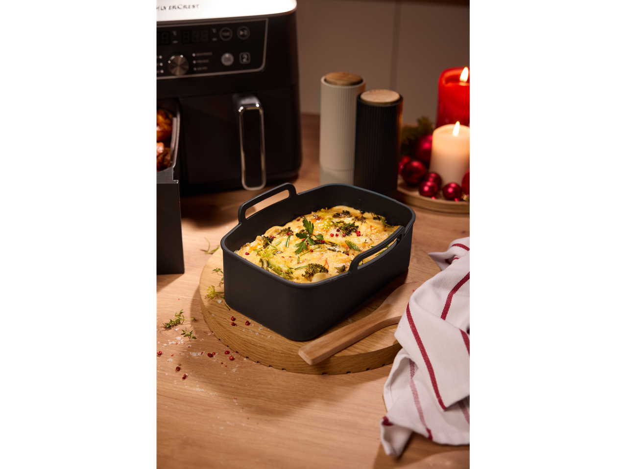 SILVERCREST® Air Fryer with a silicon insert holding a gratin, surrounded by festive decor.