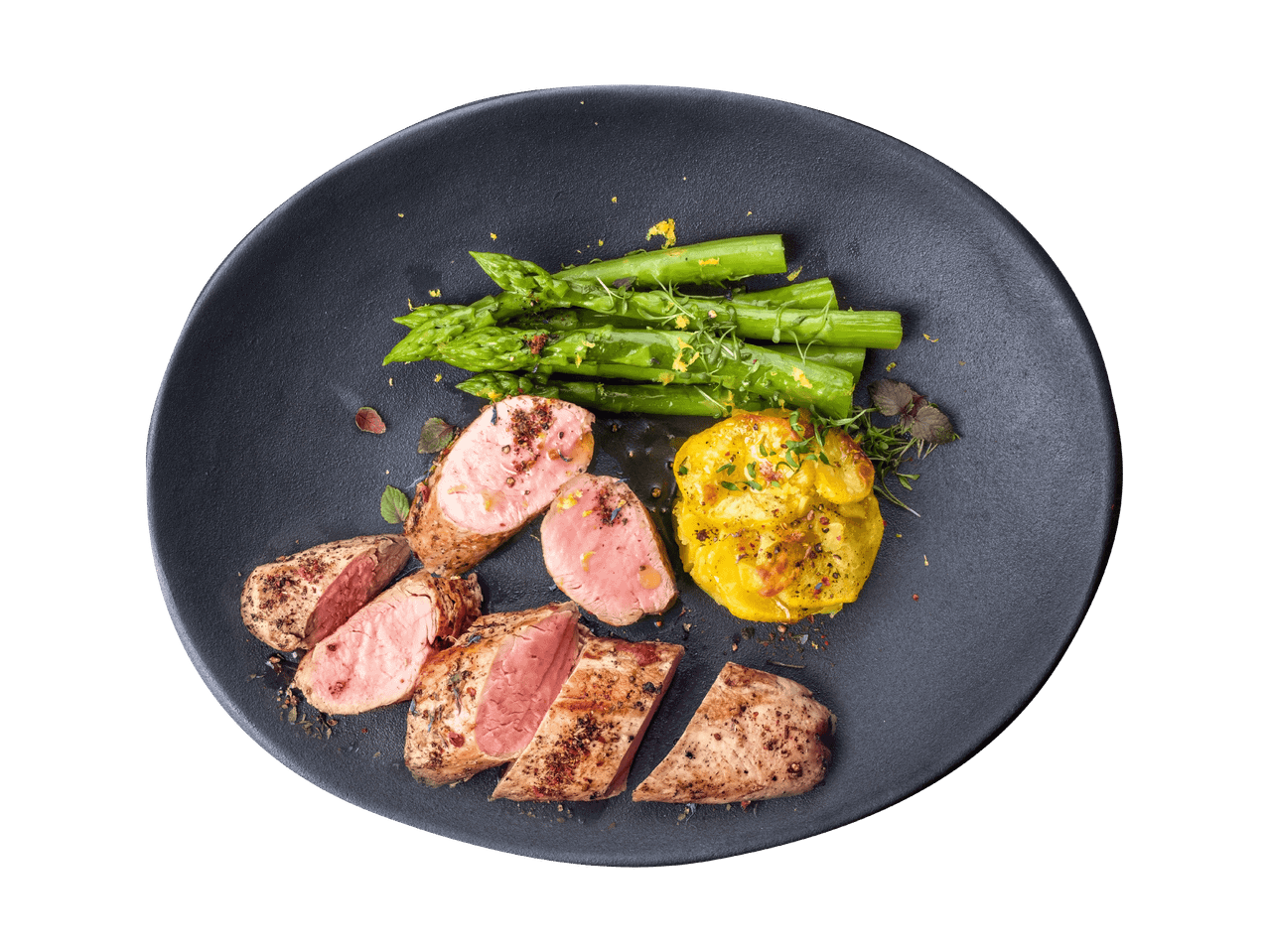 Gebratenes Schweinefilet mit grünem Spargel und zerdrückten Kartoffeln auf einem dunklen Teller.