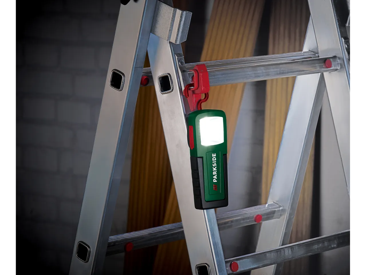 Parkside® Mini-Akku-Handleuchte okačena na merdevinama, osvetljava tamnu pozadinu.