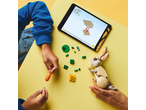 Hands building a toy rabbit with bricks, following instructions on a tablet.