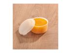 Open container of orange body scrub on a wooden surface.