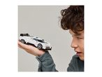 A person holding a white toy race car, looking at it intently.