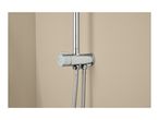 Chrome shower mixer with two flexible hoses and a control knob on a beige wall.