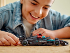 Усмихнато момче си играе с модел на състезателна кола LEGO Mercedes-AMG F1 W14 E Performance.