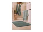 Green bath mat and towels in a bathroom with light-colored tiles.