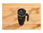 Black and gold travel mug with a handle and straw on a wooden surface.