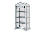 A tall, narrow, transparent greenhouse with a green frame and four wire shelves.