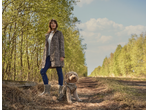 Vrouw in ESMARA luipaardprint jas en hond op bospad.