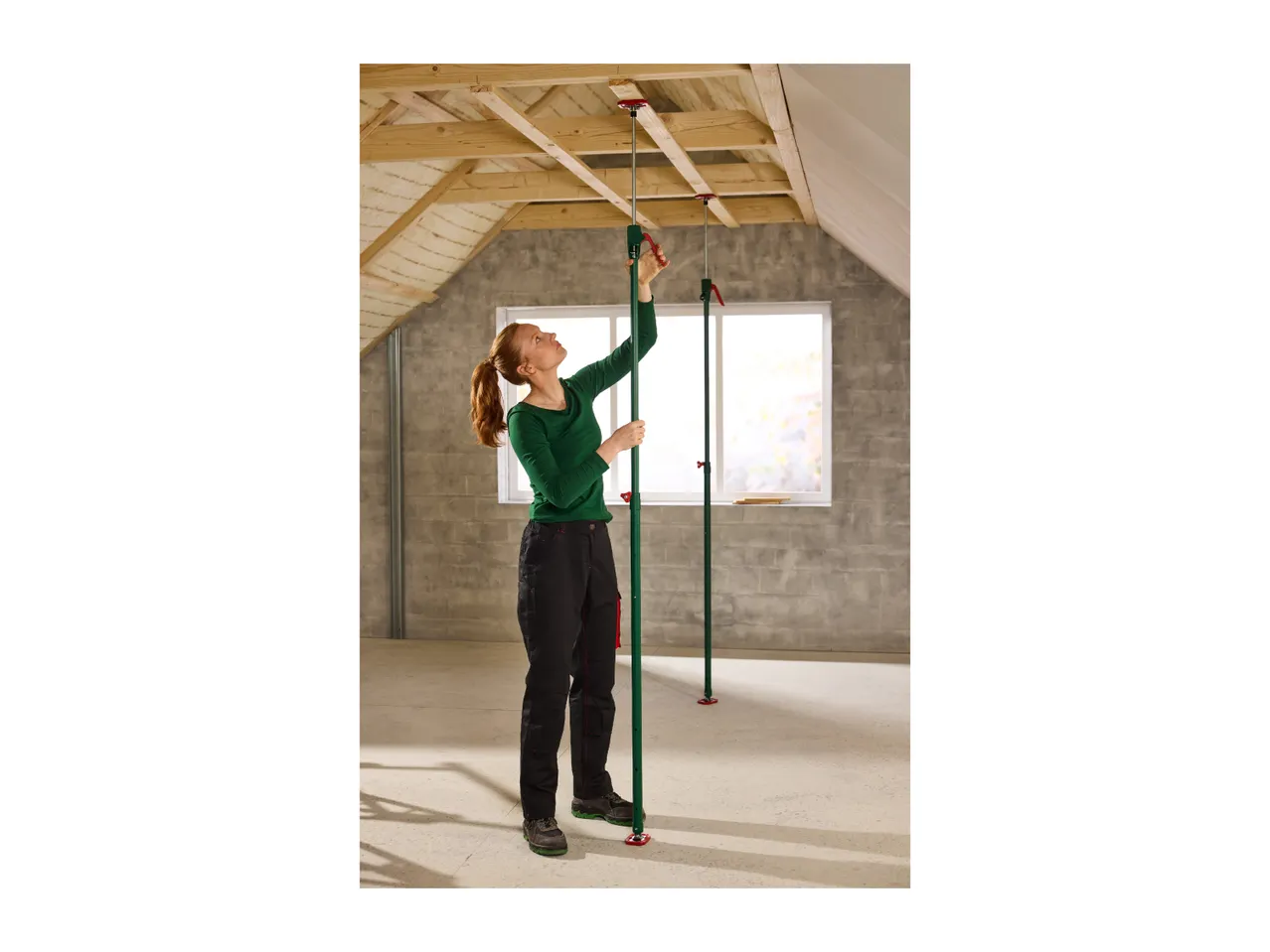 Woman installing ceiling support props in an attic with exposed wooden beams.