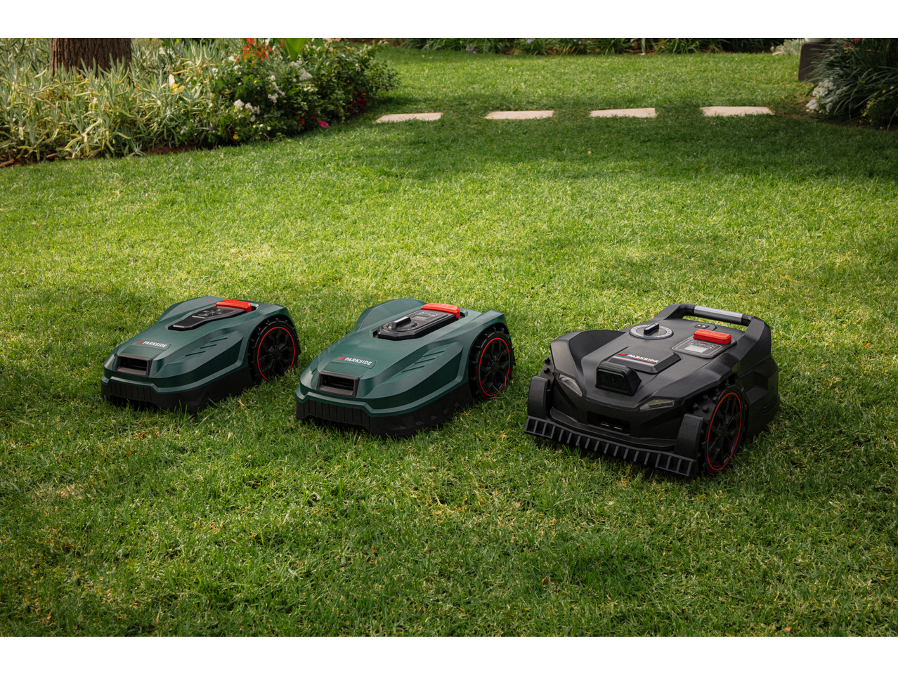 Three robotic lawnmowers, two green and one black, on a lush green lawn.