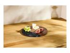 Round serving board with grapes, cheese, and figs on a wooden surface.