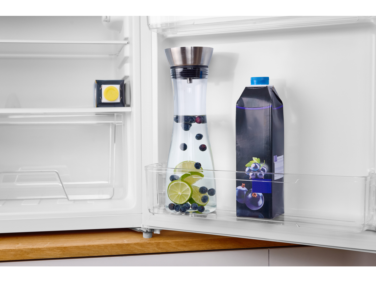 Frigider cu o carafă de apă SILVERCREST cu fructe și un carton de suc de fructe.
