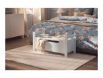 Bedroom with a white storage bench, floral duvet cover, and a beige rug.
