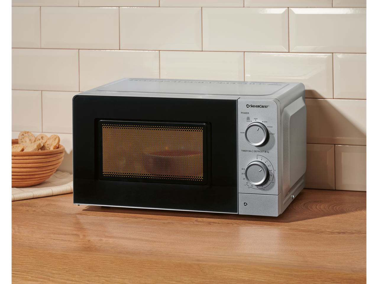 Micro-ondas SILVERCREST® 700W numa bancada de madeira com azulejos claros.