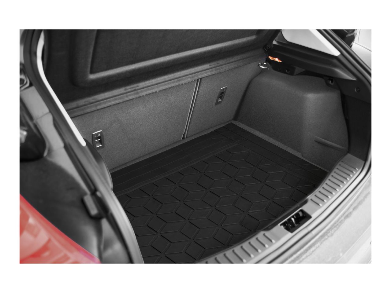 A black rubber trunk mat with a geometric pattern in the cargo area of a car.