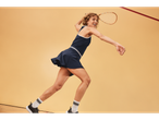 Woman playing squash wearing sportswear and racket.