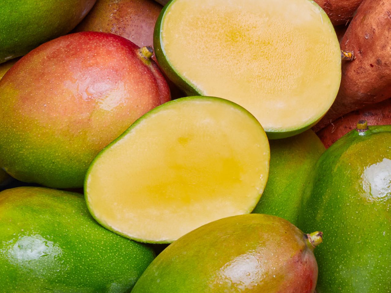 Slatki mango isečen na pola, okružen drugim mangom.