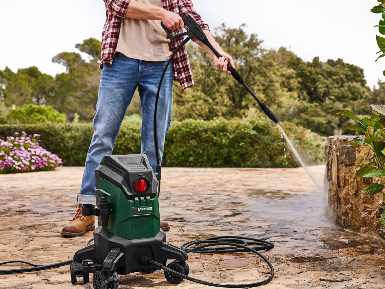 A person uses a Bosch pressure washer to clean a patio.