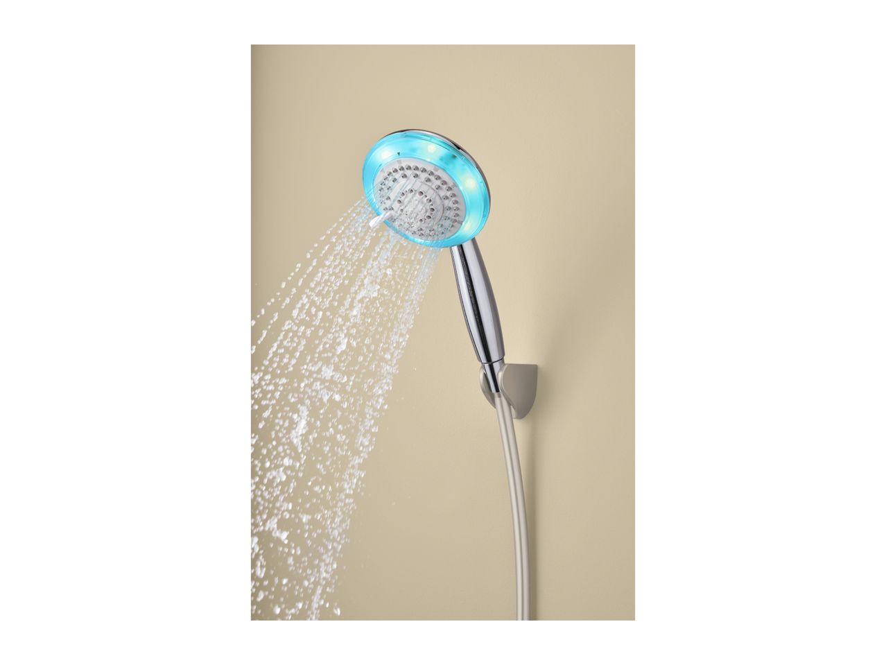 Chrome shower head with blue LED lights spraying water against a beige wall.