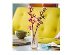 Pink and white artificial cherry blossoms in a textured glass vase on a table.