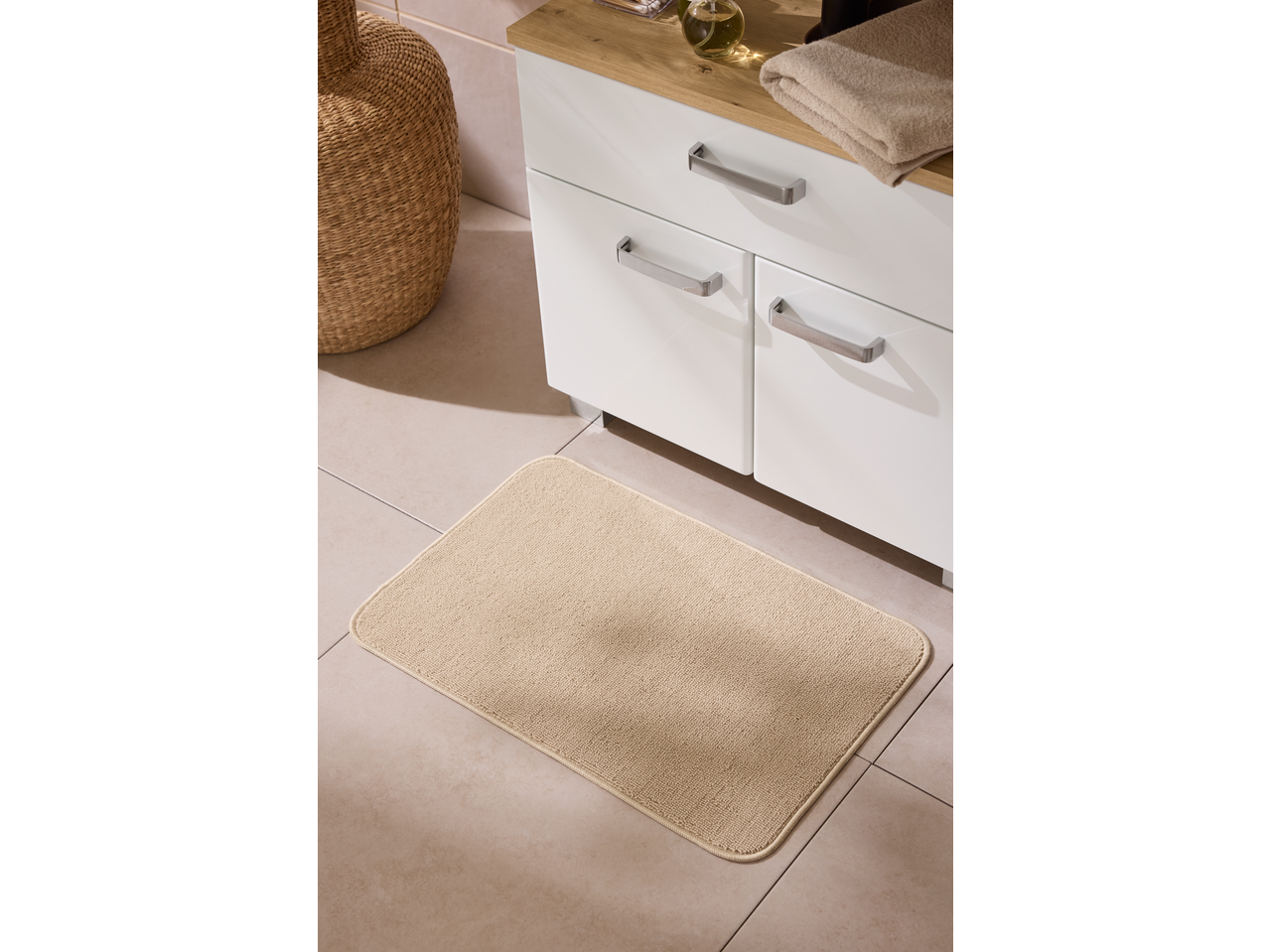 Livarno Home Bath Mat in beige, on a tiled bathroom floor next to a white vanity.