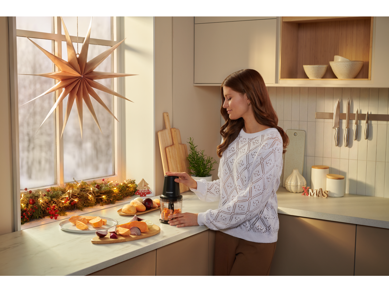 Mulher a usar o picador multifunções SILVERCREST para vegetais numa cozinha de Natal.
