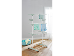 A three-tiered laundry drying rack with clothes hanging and a laundry basket nearby.