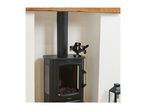 A black wood-burning stove with a heat-powered fan on top, set in a fireplace alcove.