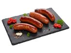 Négy sült kolbász fekete palatáblán, pirospaprikával, fokhagymával és fűszerekkel.