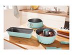 Mint green baking pans with cake batter and a finished cake on a wooden kitchen counter.