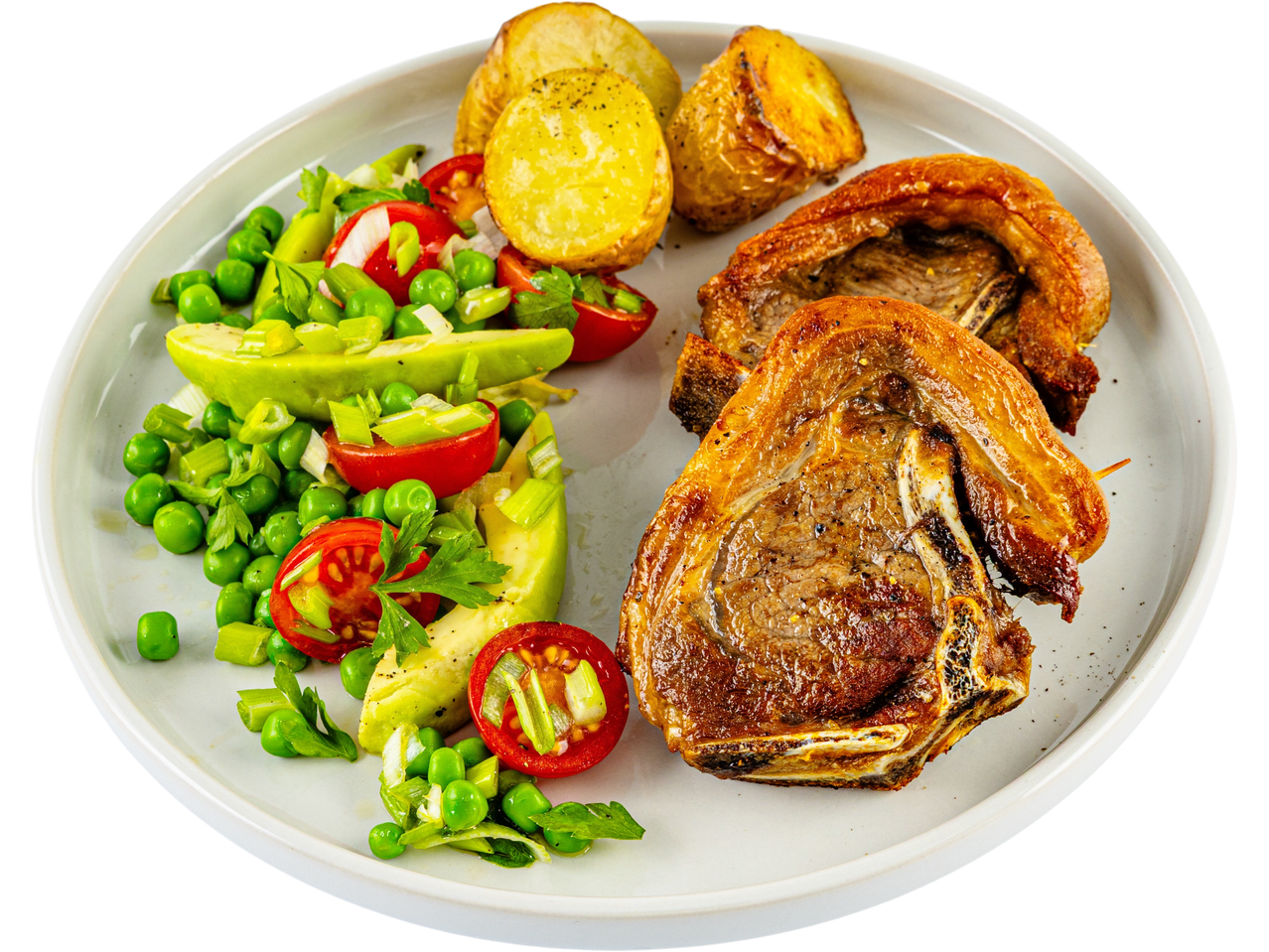 A plate of roasted lamb chops served with roasted potatoes and a fresh pea and avocado salad.
