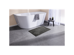 Dark gray bath mat next to a white bathtub.