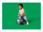 Toddler on a blue ride-on toy truck with a lion character, smiling against a green background.