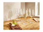 Six wine glasses, two filled with white wine, next to a cheese and grape board.