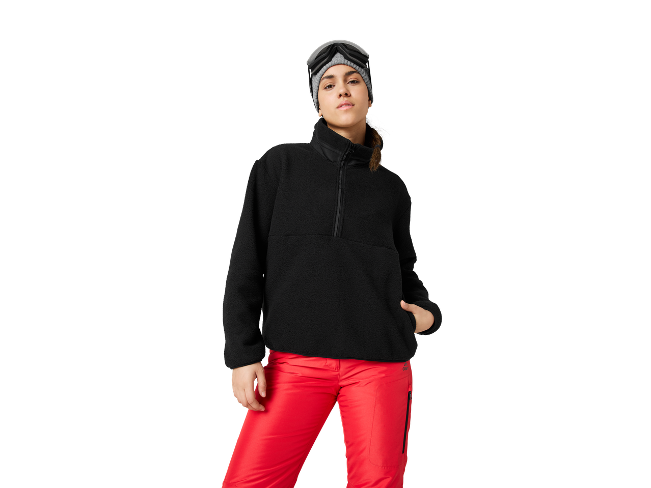 Woman in black fleece and red ski pants with ski goggles and beanie