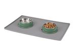Two green pet bowls, one with food and one empty, on a grey silicone mat.