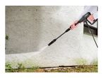 Person cleaning a dirty wall with a pressure washer, showing before and after cleaning.