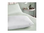 White striped pillow on a light green bed with a bedside table and lamp.