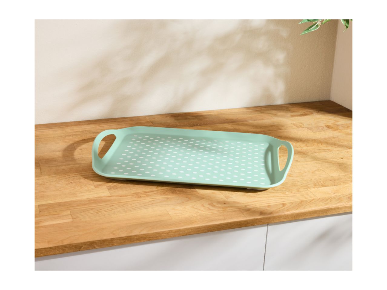 Mint green rectangular serving tray with white polka dots on a wooden countertop.
