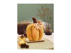 A fluffy orange pumpkin decoration with a brown stem and raffia bow, surrounded by fall decor.