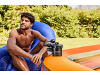 Man sitting on a blue inflatable chair next to a CRIVIT electric pump and orange paddling pool.