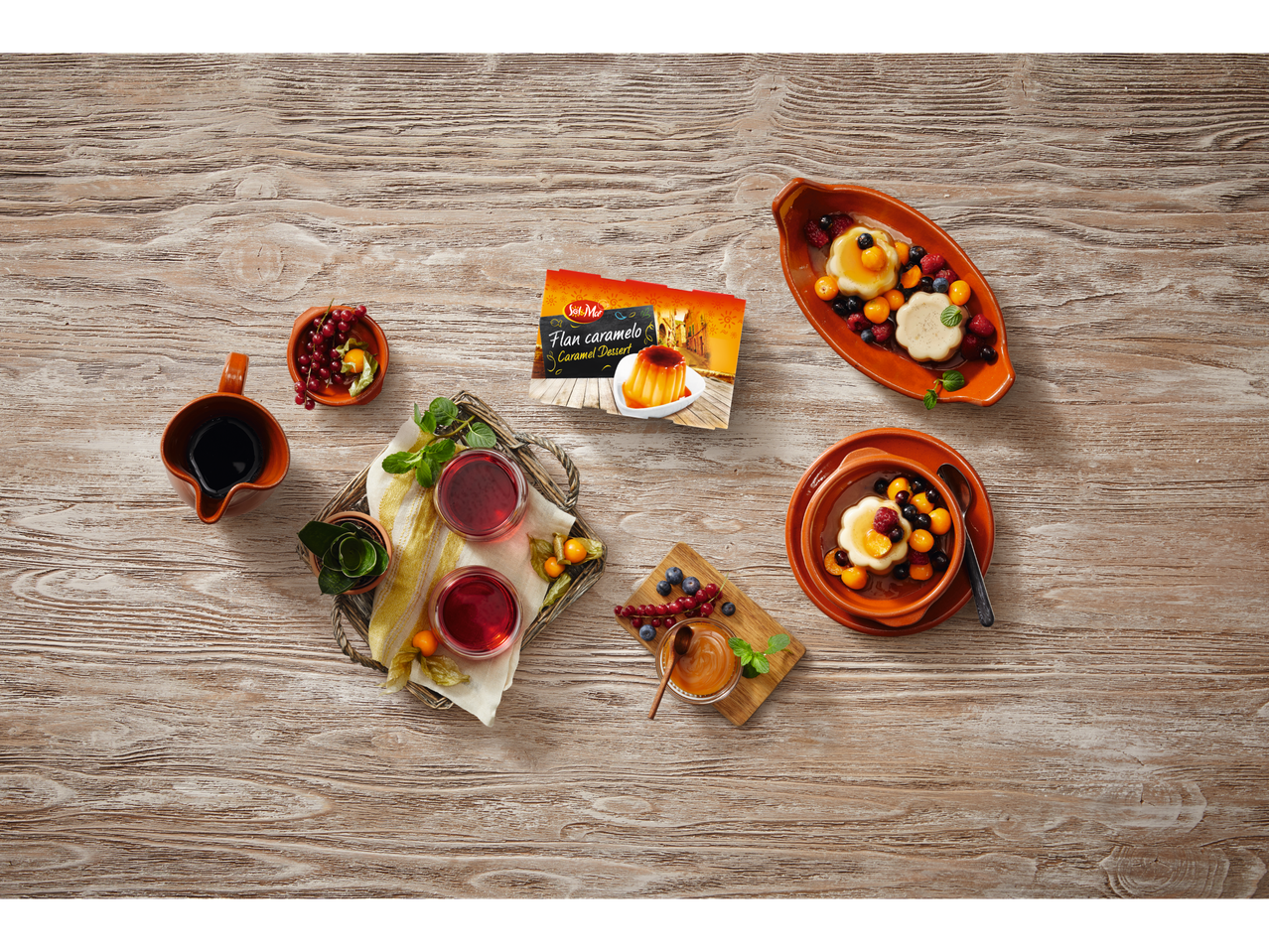 Zonnige foto van Solo-flan, bessen en drankjes op een houten tafel.