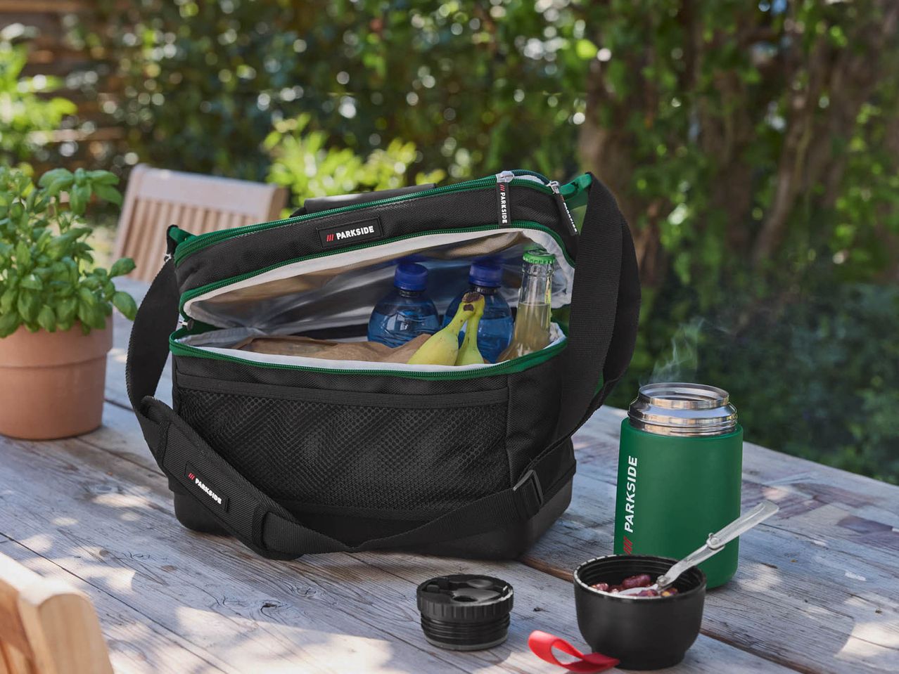 Parkside cooler bag with food and drinks on a wooden table outdoors.