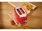 Red Silvercrest toaster with toast and jam on a wooden surface.