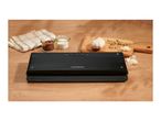 Black vacuum sealer on a wooden table next to kitchen ingredients